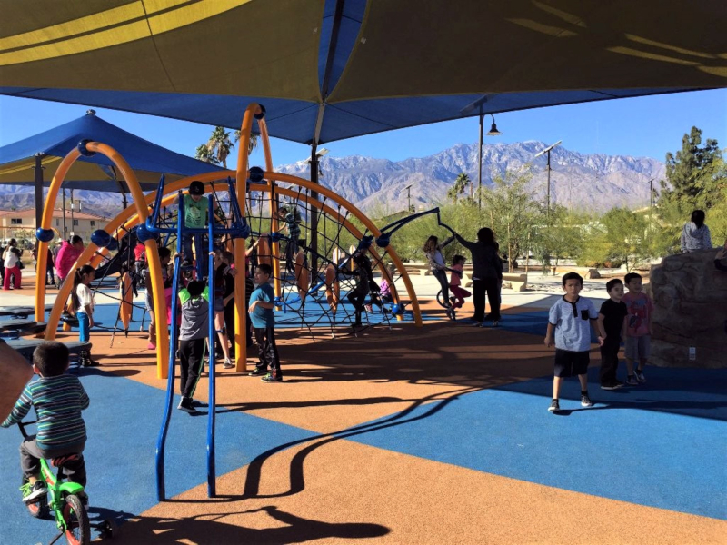 Kids on play equipment under awning at park