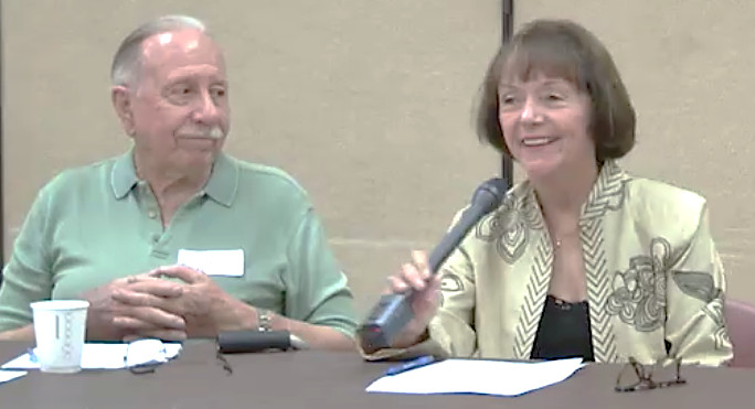 Person talking into a microphone while another person watches