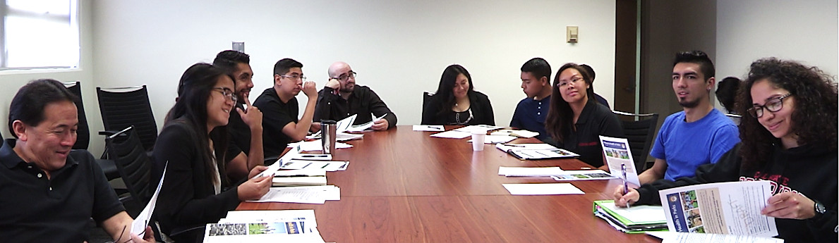 A group of people sitting at a conference table talking and looking over documents