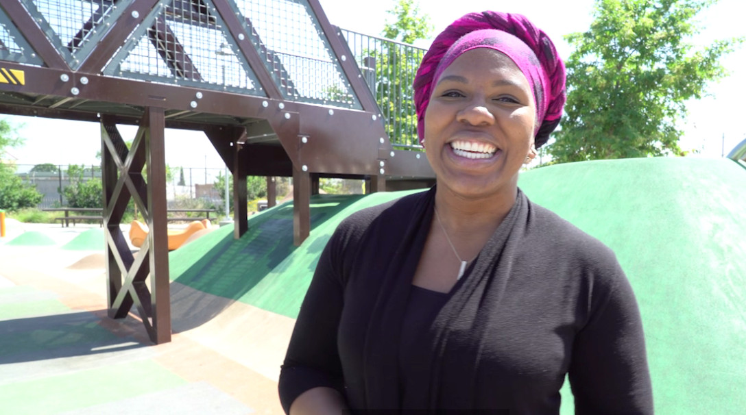 Person smiling next to a metal bridge in a playground