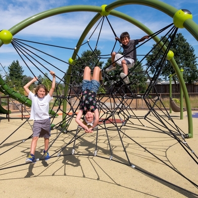 Three teenagers playing on a rope play structure in Bayer Park