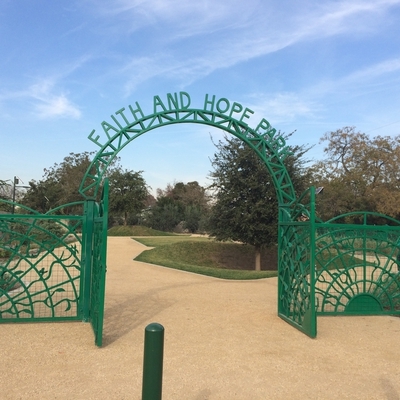 Green ornamented iron gate fence with letters that read Faith and Hope Park