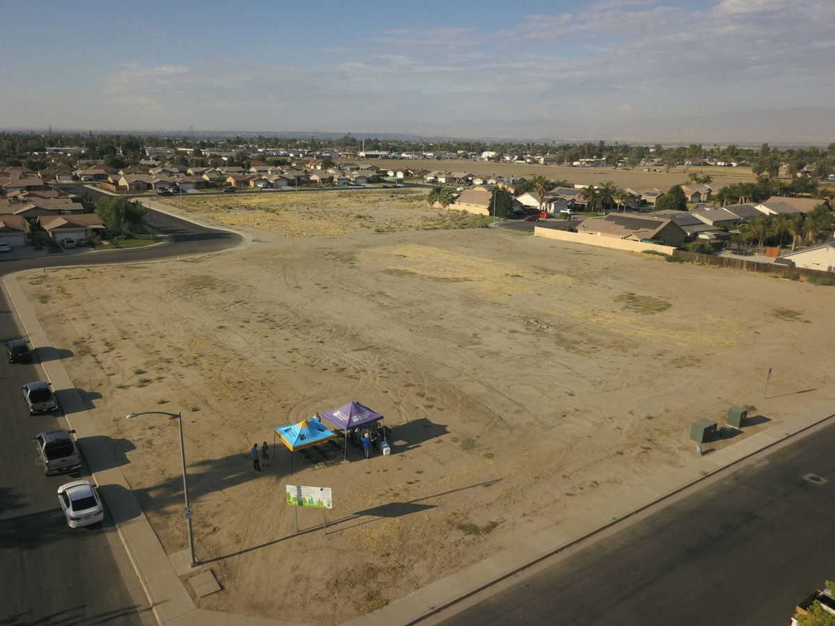 Vacant dirt lot with a sign announcing the Linnell-Brahma Park