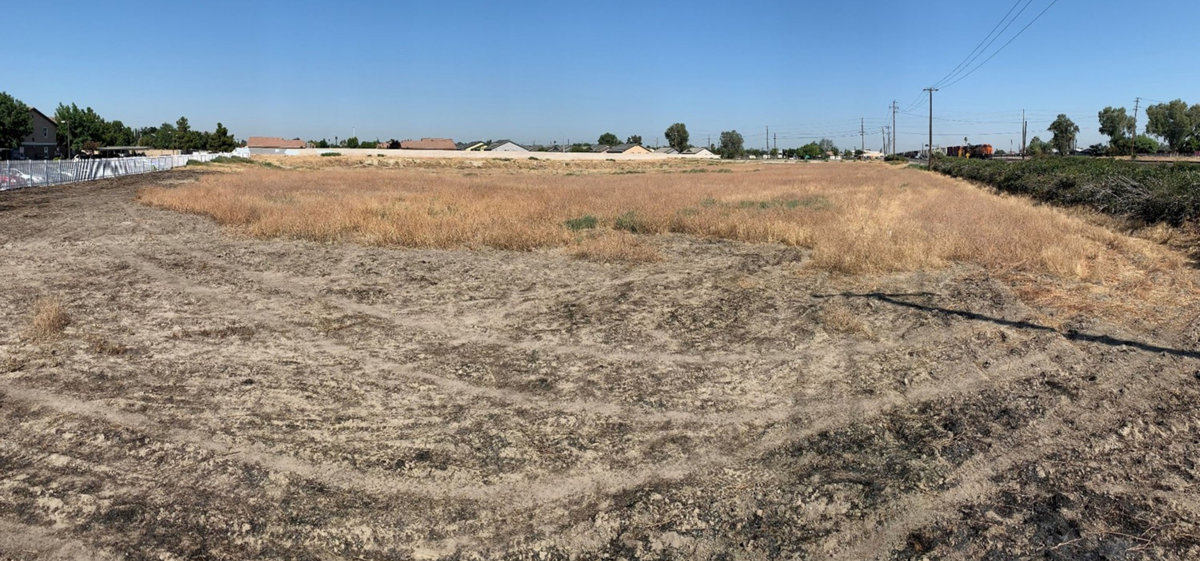 Vacant dirt lot with power lines in the distance