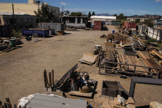 Dirt lot filled with containers, construction materials and machinery.