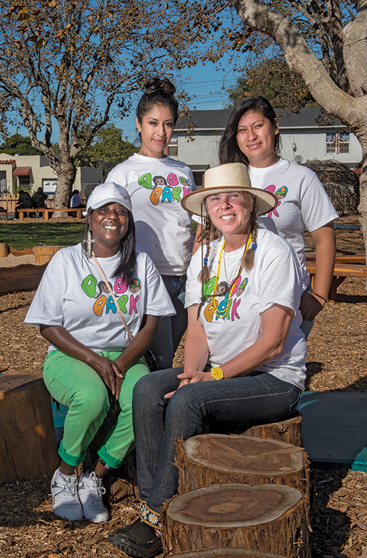 A dark-skinned woman, two medium-skinned women and a light-skinned woman, pose for a photo outside