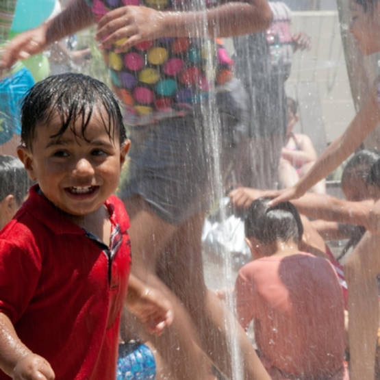 Children smiling and playing in sprinkler at Washington Elementary Natural Park