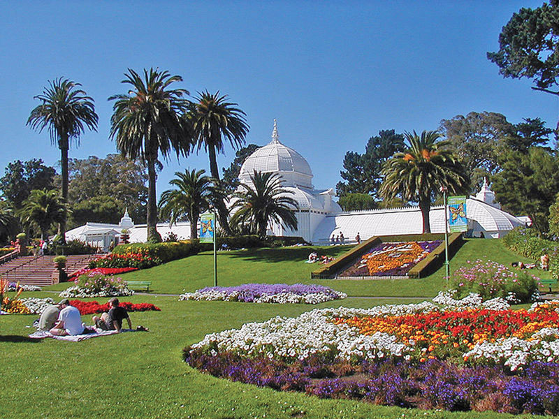 People picnicking on the grass in front of the Golden Gate Park Conservatory of Flowers
