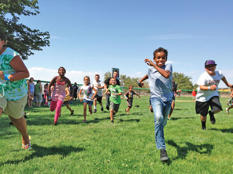 Children running in a race on a grassy sports field