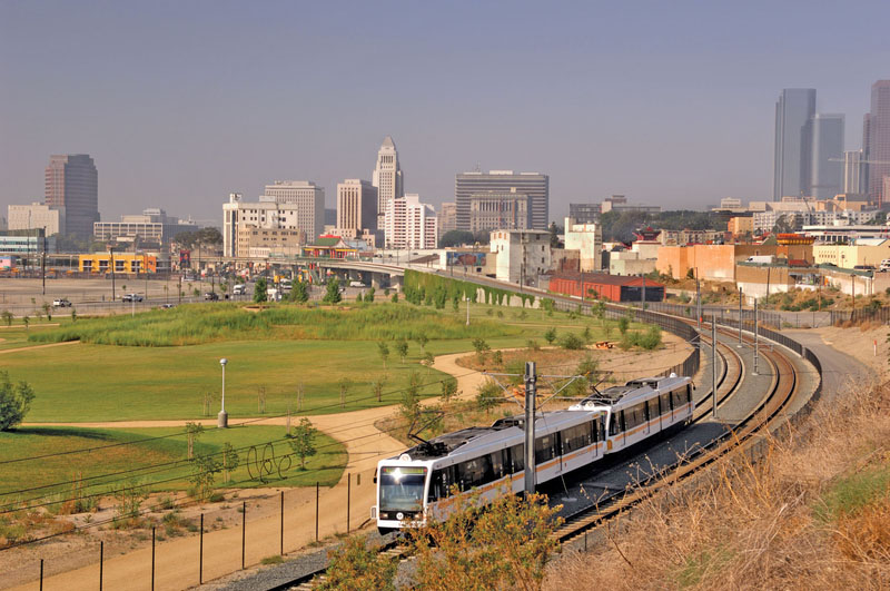 A Los Angeles Metro train passes the Los Angeles State Historic Park with Downtown in the background