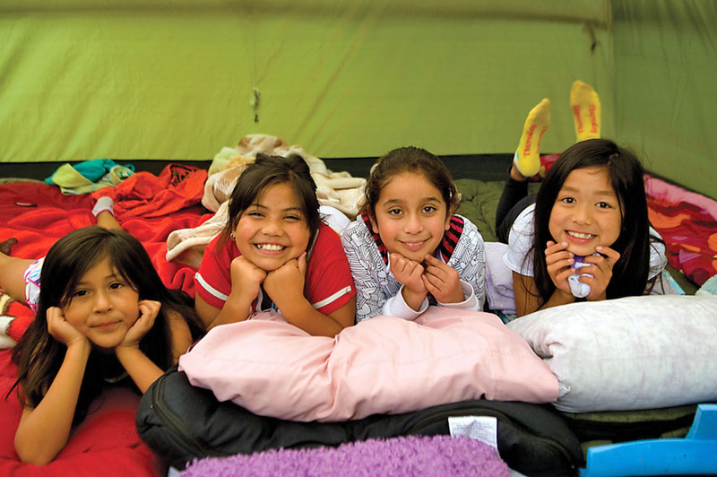 Four girls hanging out in a tent on a camping trip