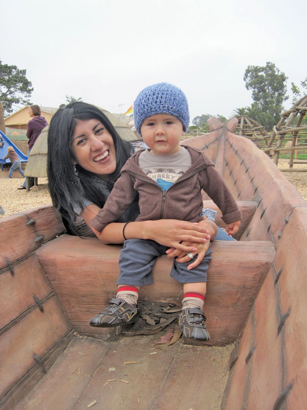 A woman and her toddler sitting in a play structure designed to look like a wooden boat