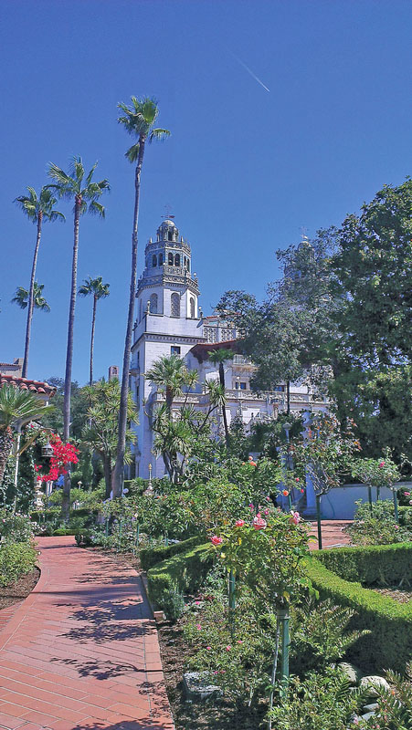 Hearst San Simeon monument with blue skies, palm trees, and brick pathway