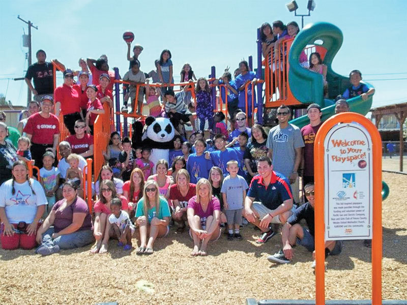 A large group of families on and in front of a new playground.