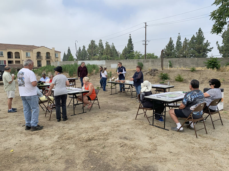 15 individuals gathered in smaller groups and drawing over printed aerial images of a park