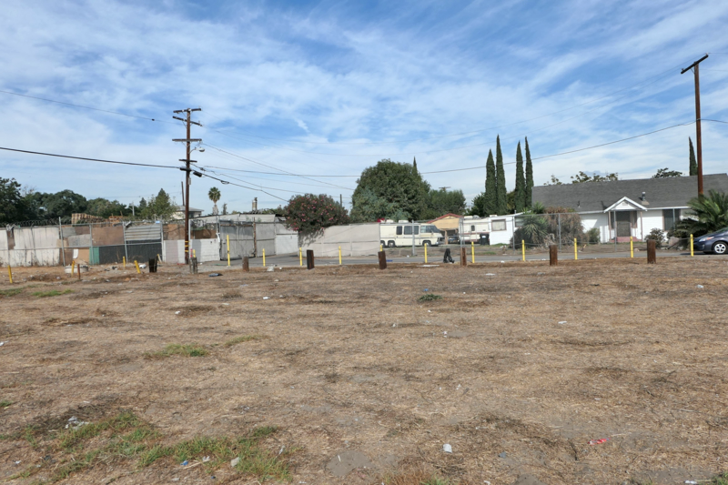 Vacant dirt lot near residential homes.