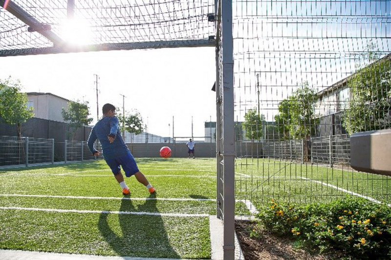 Man at the soccer goal kicking a ball.