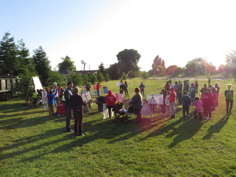 People of all ages gathered outside during an evening meeting.