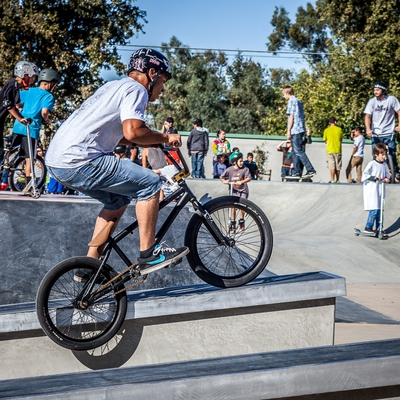 Young adult wearing a helment doing tricks with his bicycle on a ramp.