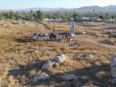 aerial image of a vacant lot with a large grouop of people gathered in the middle.