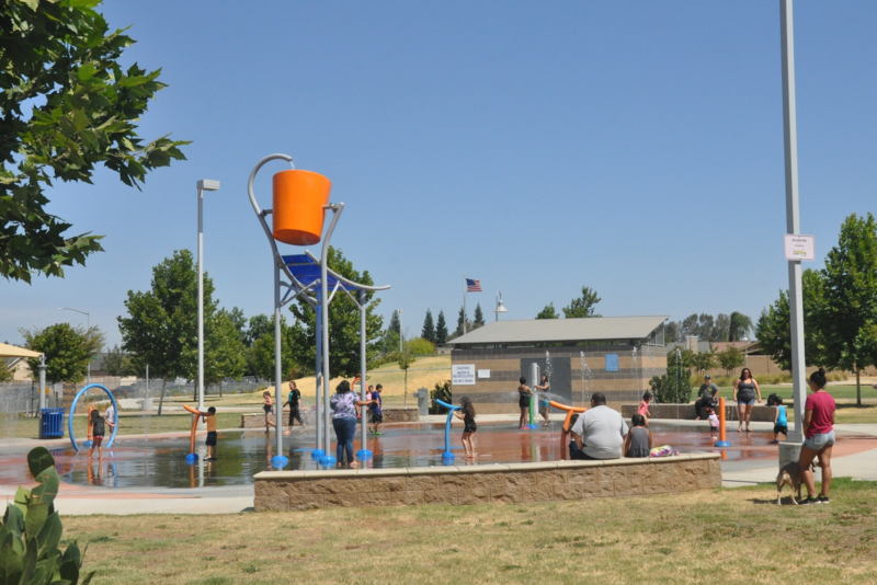 Kids and adults play with water in a park.