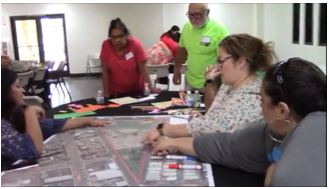 Multiple women point and draw on a large print of a park.