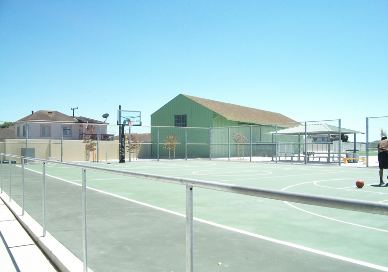 Outside basketball court with a single basketball hoop.