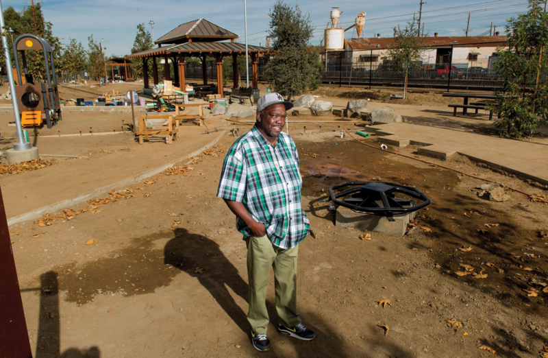 Man standing in front of partly constructec wooden canopy and construction.