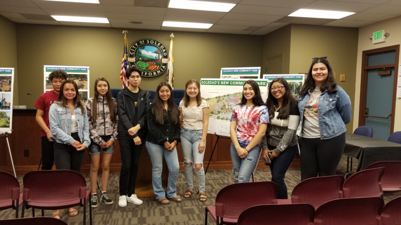 Group of young adults pose infront of printed presentation boards