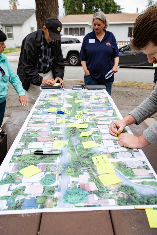 People using sticky notes to add their ideas to a large printed aerial view of a neighborhood.