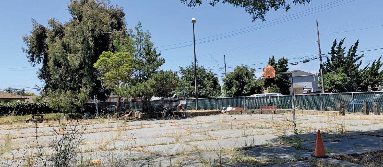 Unkept park with old basketball hoops and overgrown grass.