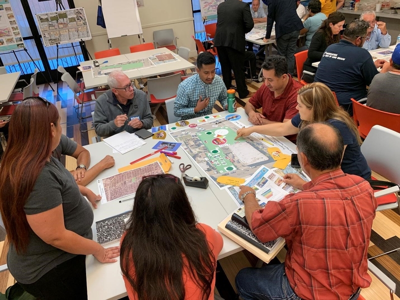 Group of people of varied genders and ages at a table pointing to a printed image of a park