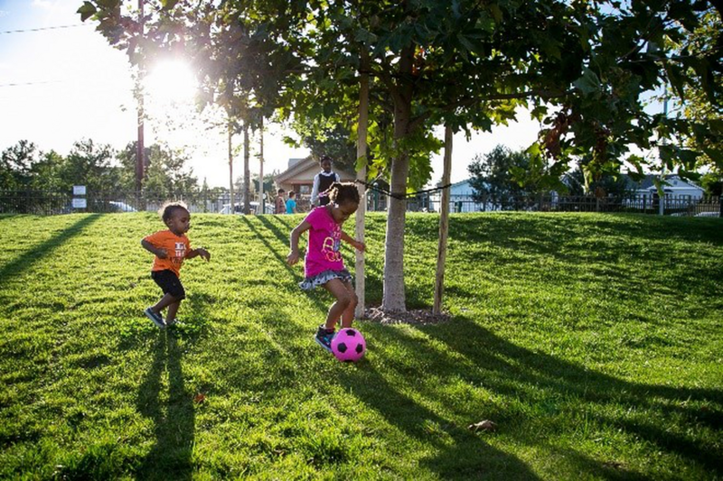 Two kids playing with a soccer ball on a grassy field.