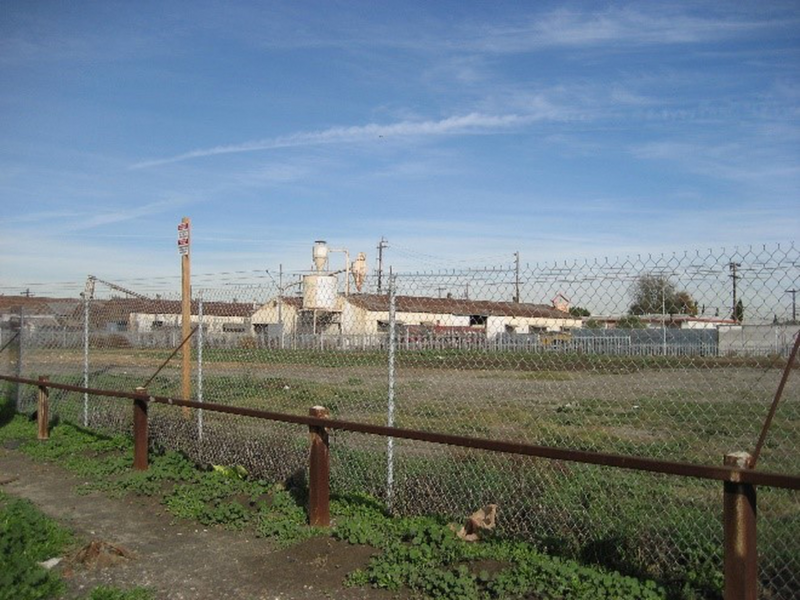 Vacant lot with grass behind chainlink fence.