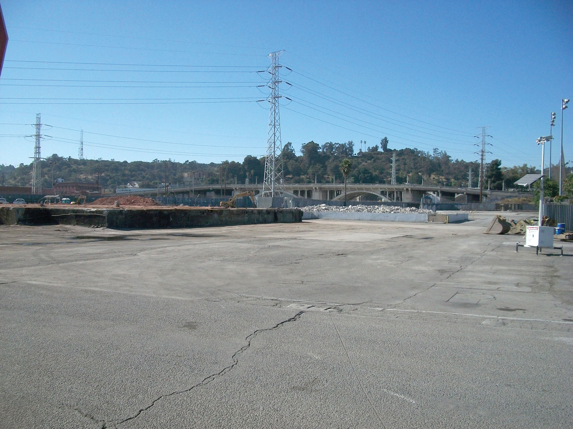 A cracked pavement lot with power lines in the background