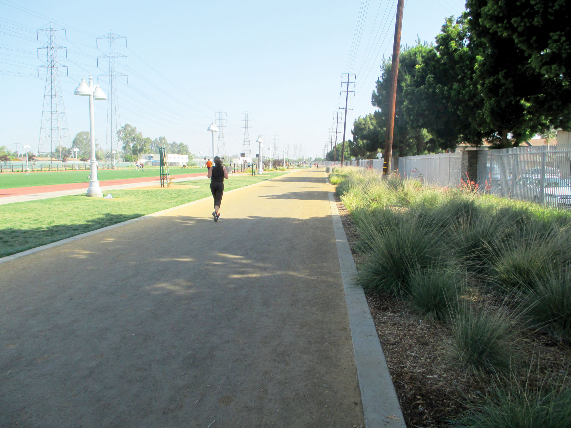 A woman jogging on a new compacted dirt track on a sunny day