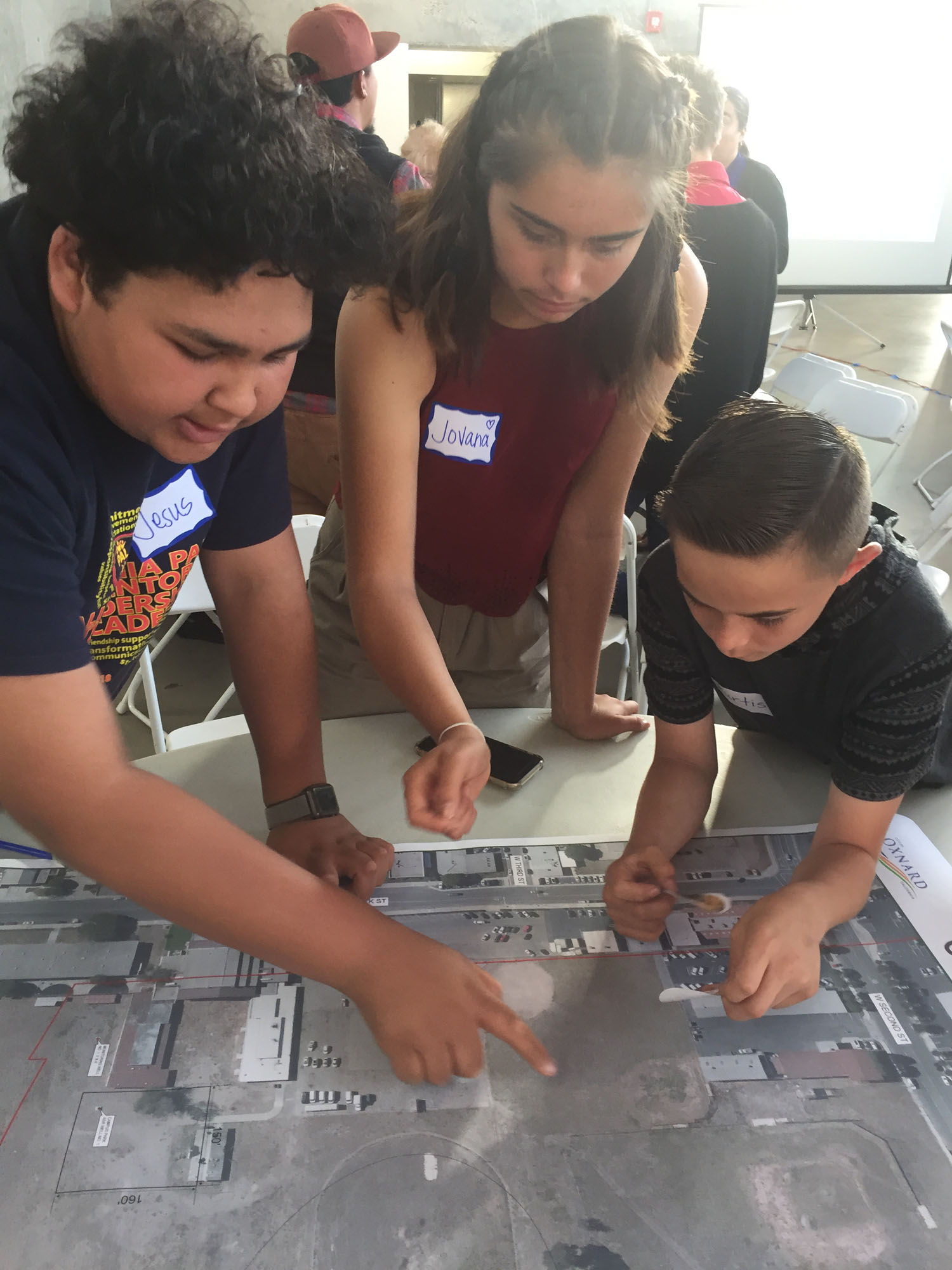Three children review an aerial photograph of a schoolyard during a planning process