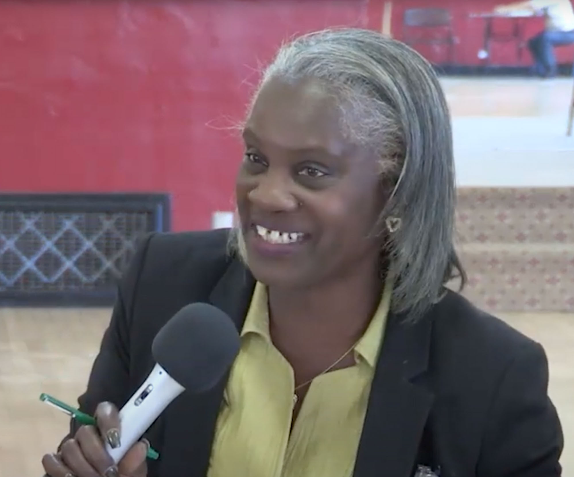 A smiling woman talking into a microphone at a park planning meeting