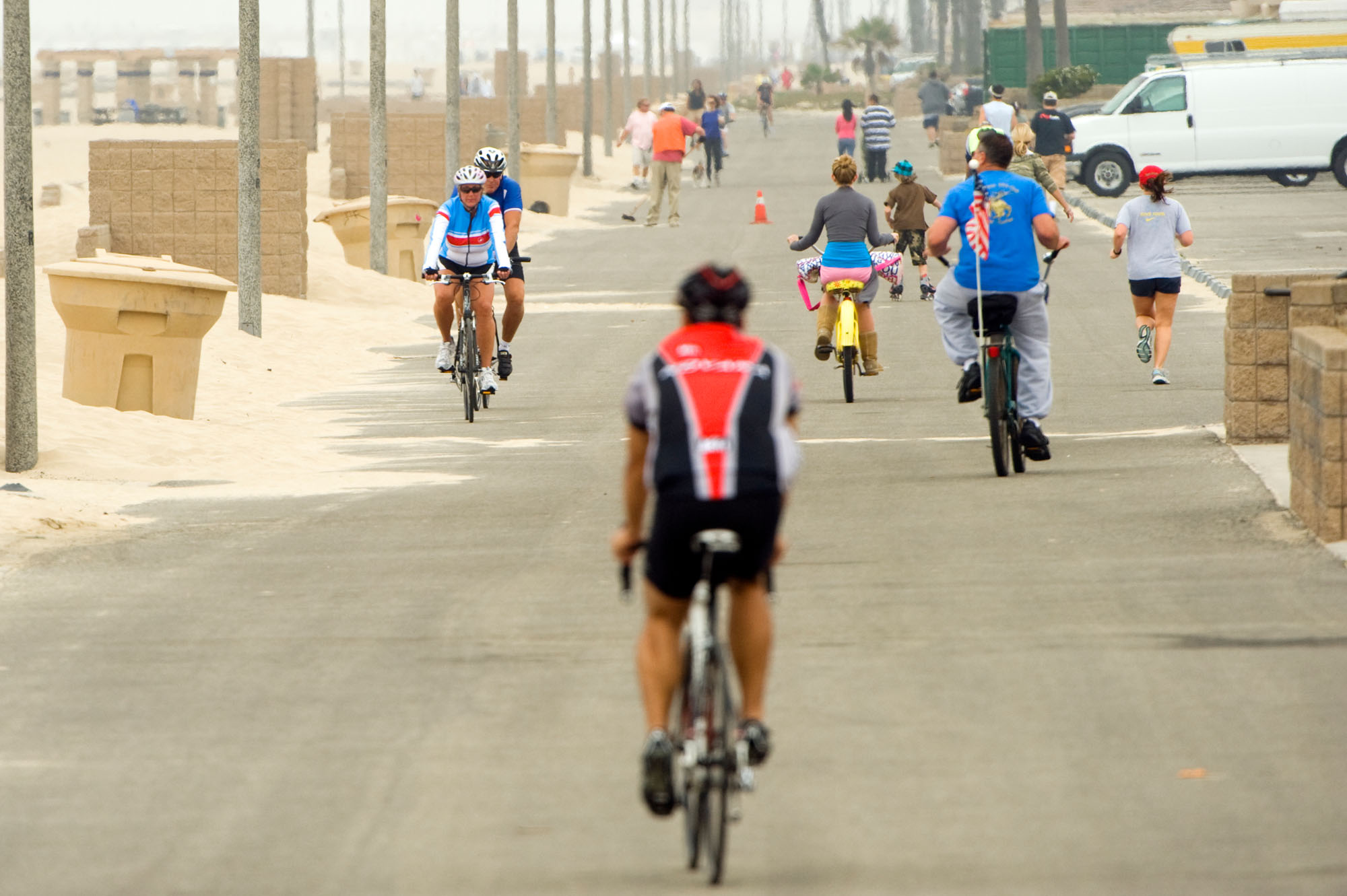 People bicycling and jogging on a road next to the beach