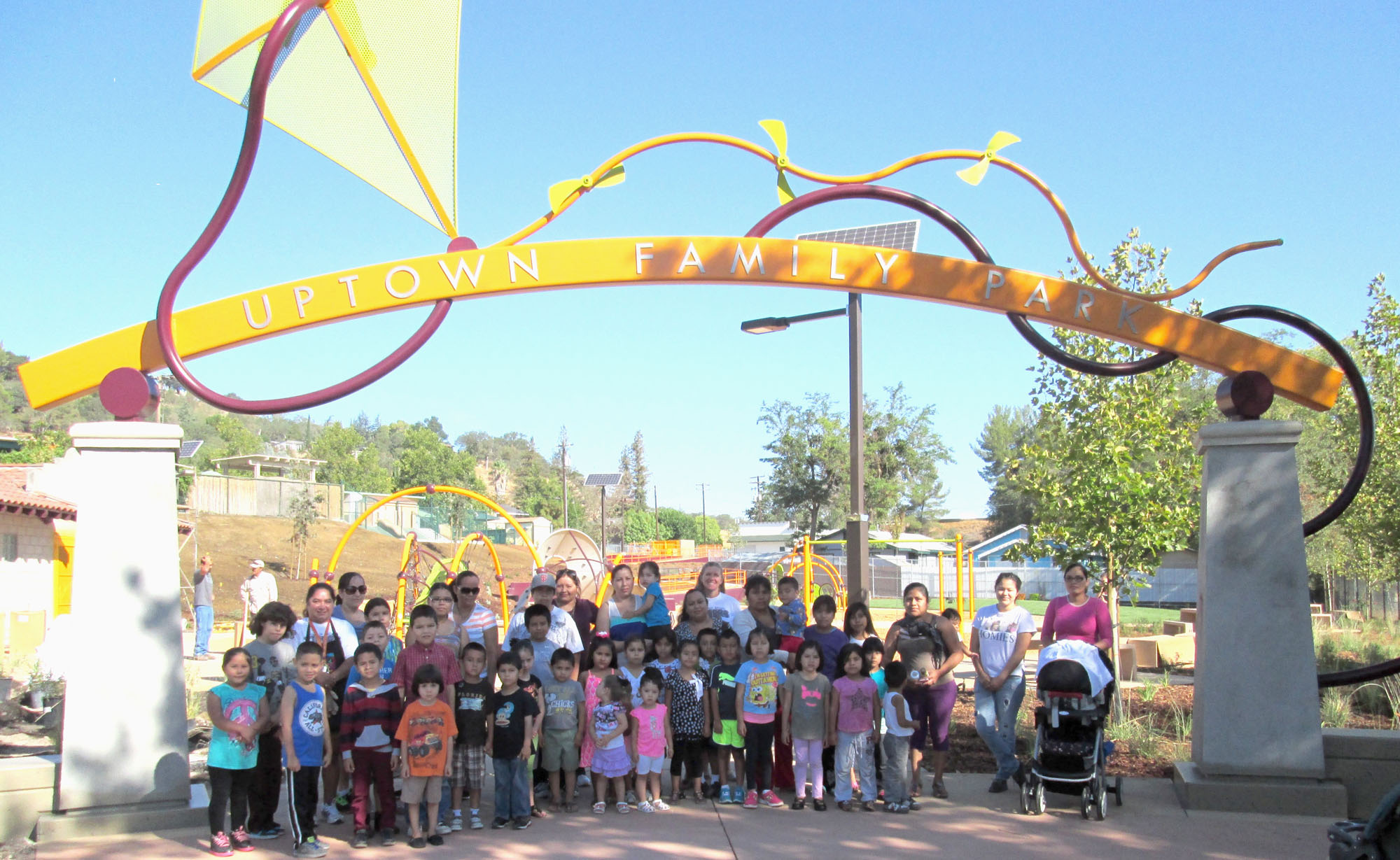 Families pose for a photo under the Uptown Family Park entrance sign