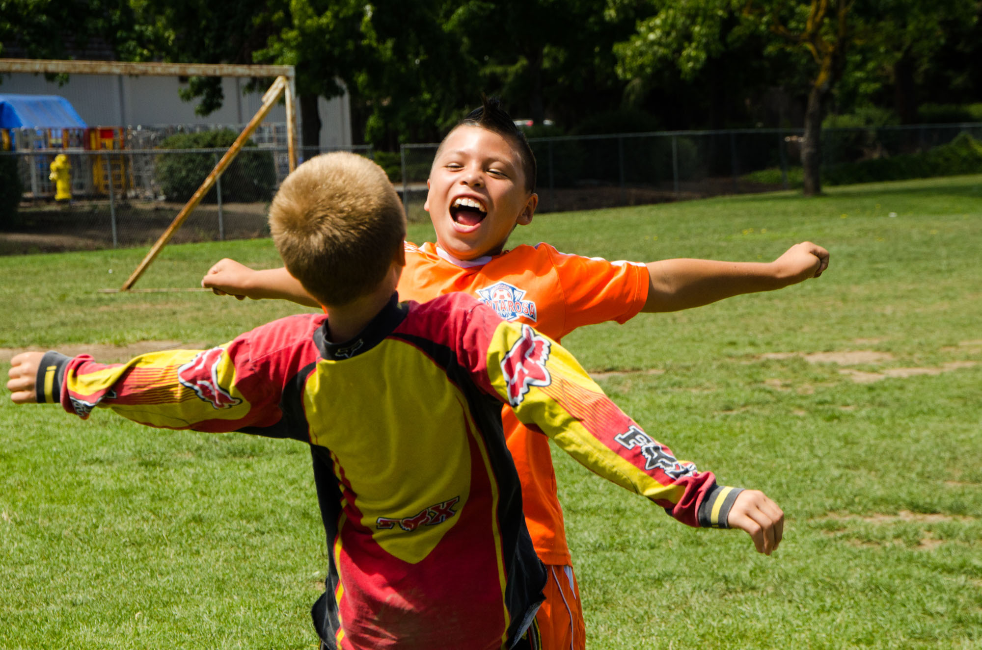 Two children on a soccer pitch jumping and chest bumping
