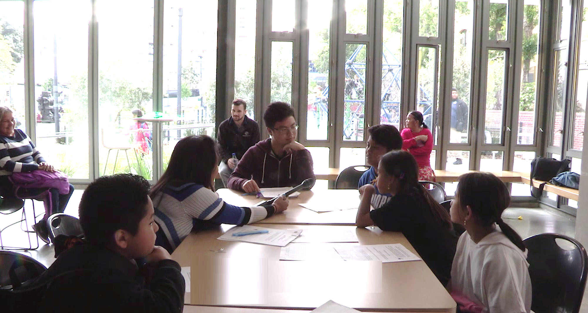 A group of students being interviewed sitting around a table in a light filled room