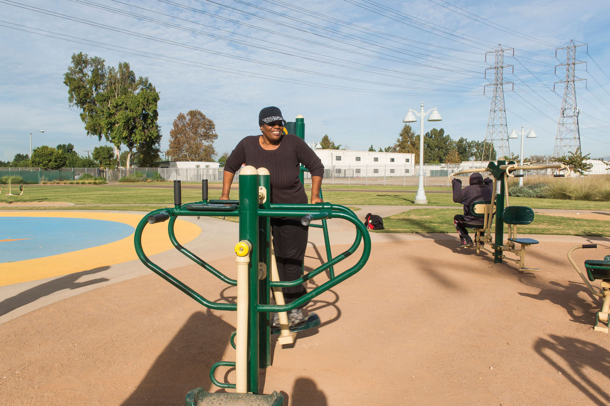 A woman smiles as she exercises on outdoor equipment