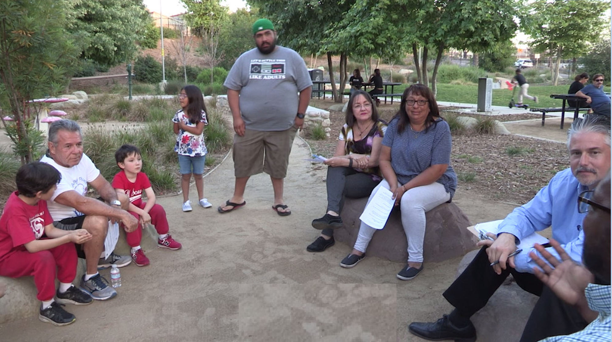 Families gathering in a new park space having a discussion about playgrounds