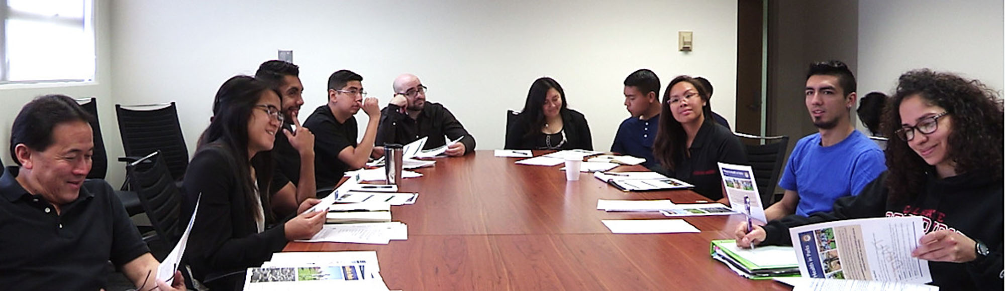 A group of people sitting around a conference table reviewing and discussing a parks report