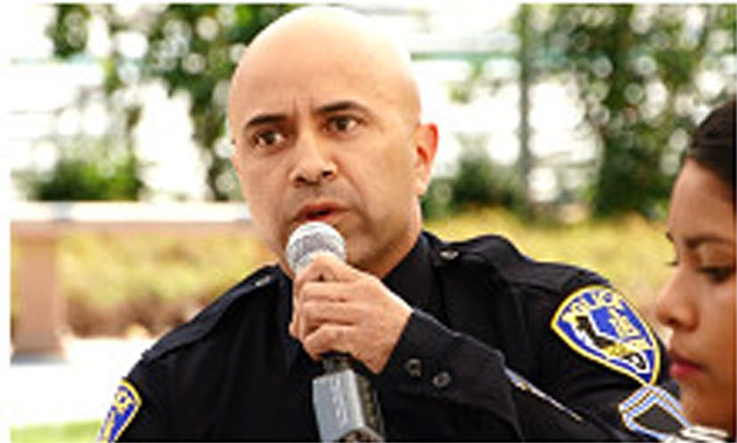 A police officer outside speaking into a microphone